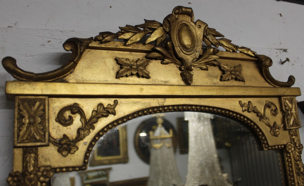 A pair of gilded Neoclassical wall mirrors featuring decorative top cresting, beaded frames, and integrated candle sconces at the base. View V
