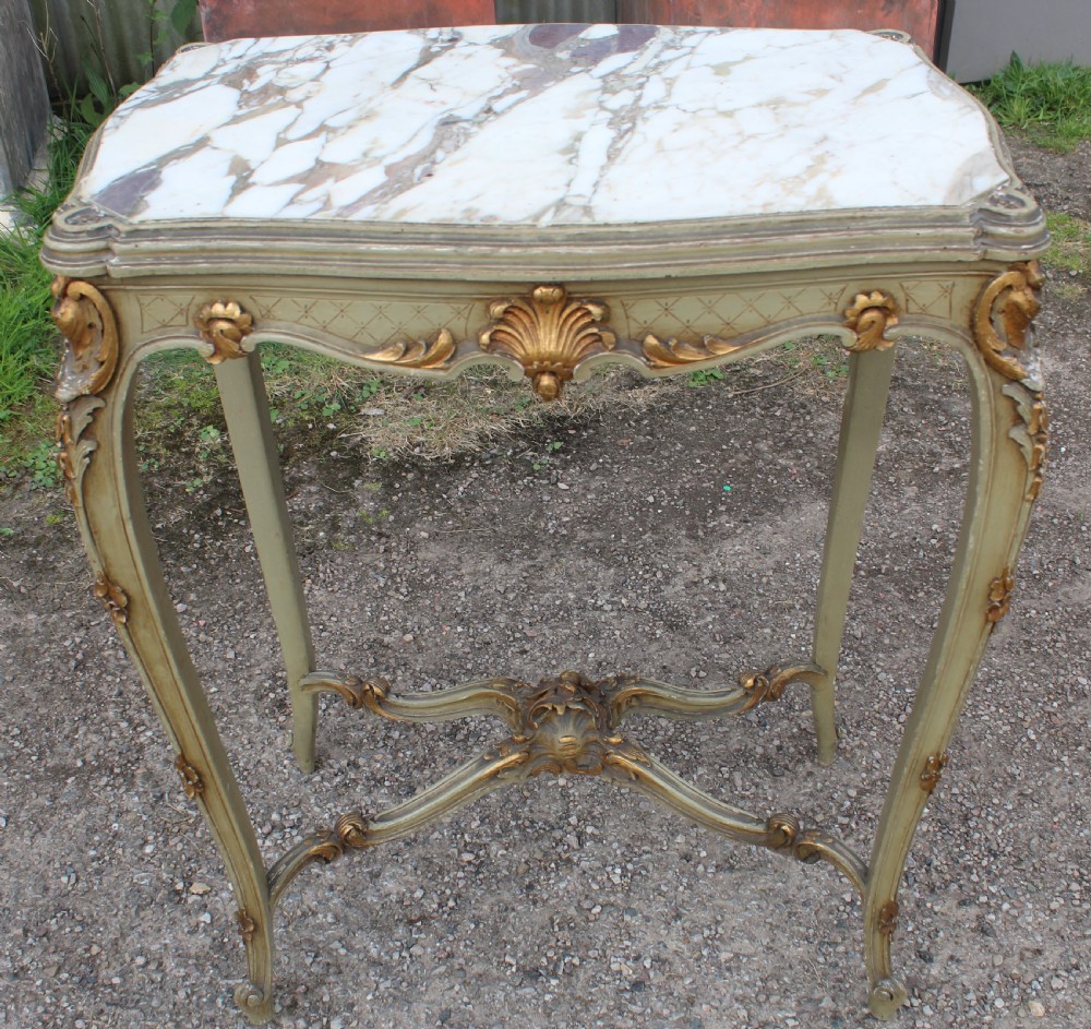 A Louis XV style side table featuring a white and grey veined marble top resting on a painted frame with gilded shell motifs and cabriole legs.