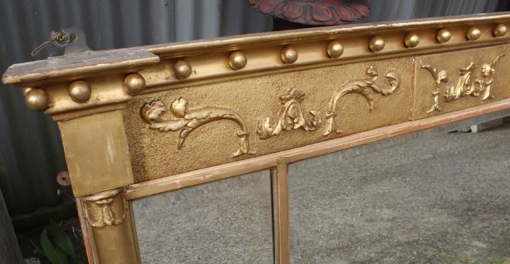 A wide gilded landscape overmantel mirror featuring three glass panels flanked by fluted columns and topped with a decorative foliate frieze. View II