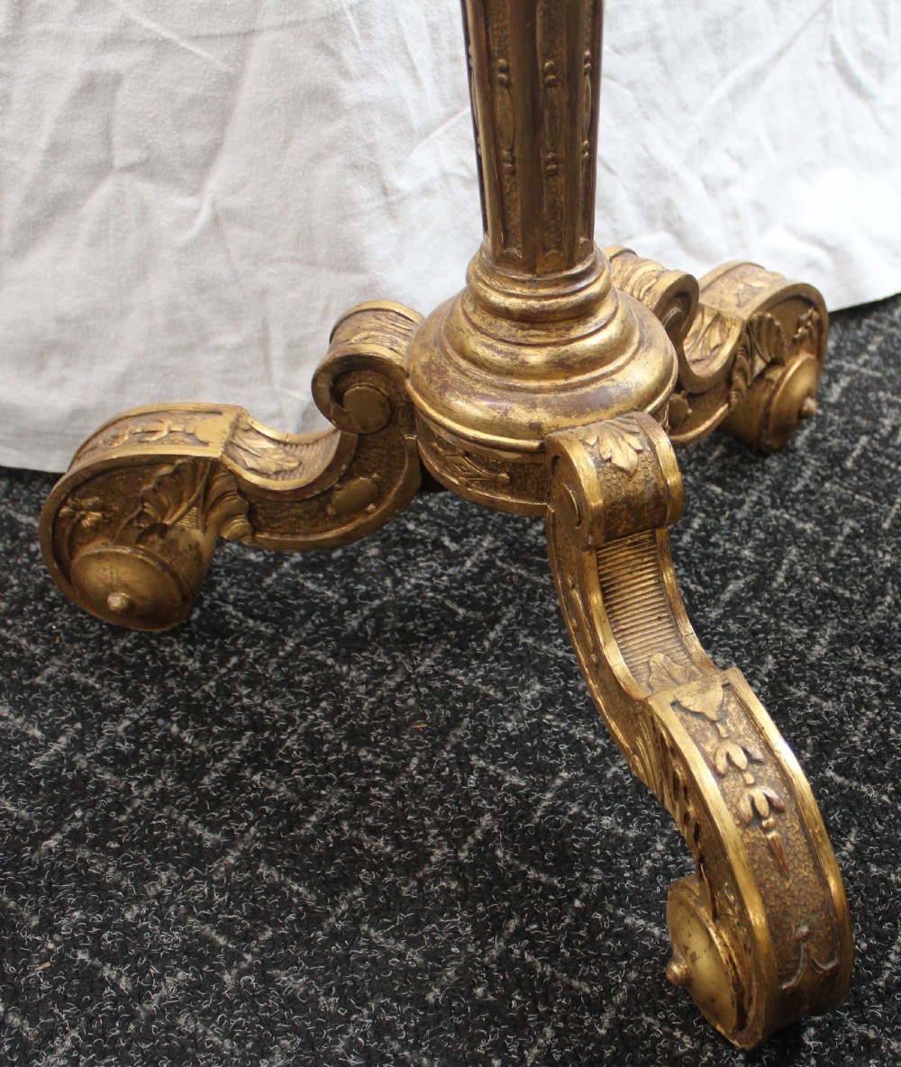 A tall giltwood torchere stand featuring a circular carved top, a fluted turned stem, and a scroll-footed tripod base. View IV