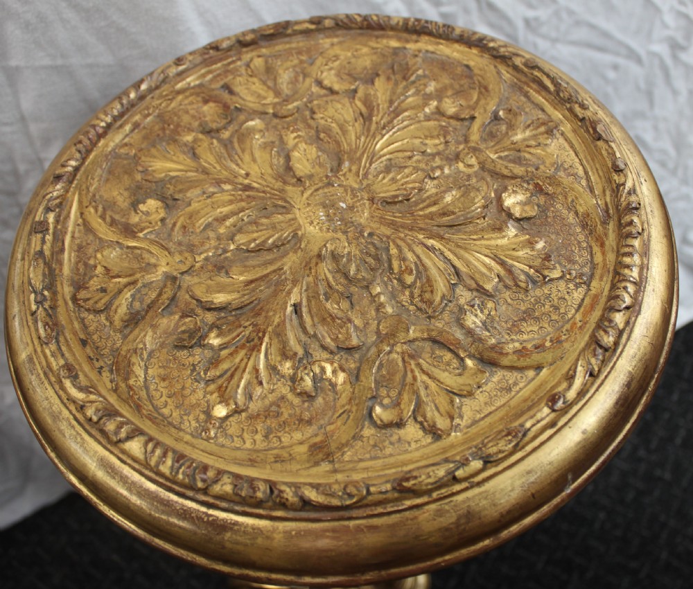 A tall giltwood torchere stand featuring a circular carved top, a fluted turned stem, and a scroll-footed tripod base. View V
