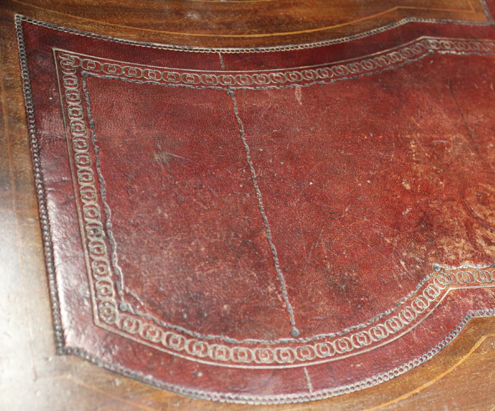 An Edwardian mahogany writing desk featuring intricate floral marquetry, a red gilt-tooled leather writing surface, a raised superstructure with drawers, and tapered legs on brass castors. View VII