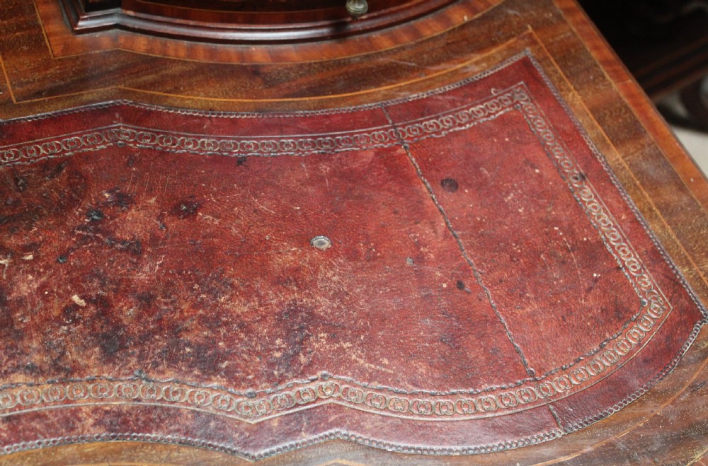An Edwardian mahogany writing desk featuring intricate floral marquetry, a red gilt-tooled leather writing surface, a raised superstructure with drawers, and tapered legs on brass castors. View VIII
