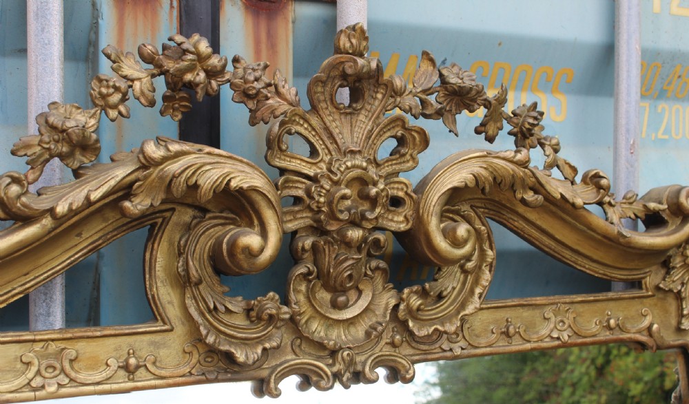 A large French Rococo style overmantel mirror featuring an ornate gilded frame with detailed floral and scrollwork carvings. View II