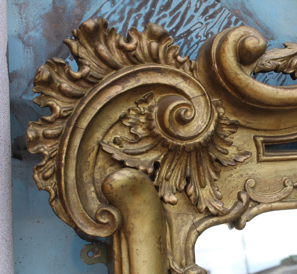 A large French Rococo style overmantel mirror featuring an ornate gilded frame with detailed floral and scrollwork carvings. View III