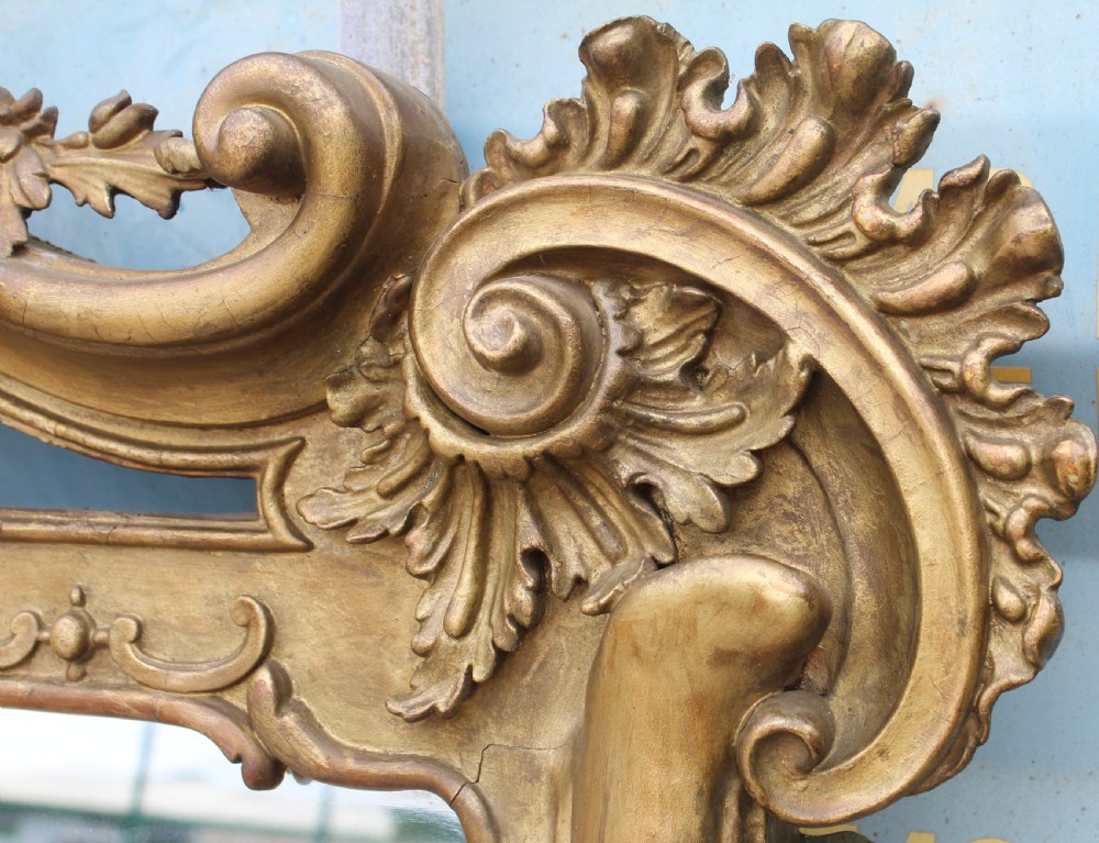 A large French Rococo style overmantel mirror featuring an ornate gilded frame with detailed floral and scrollwork carvings. View V