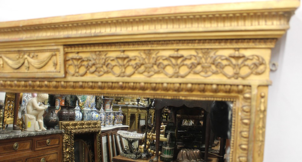A large rectangular gilded overmantel mirror featuring a moulded frame with floral swags, a guilloche frieze, and decorative plinth bases. View III