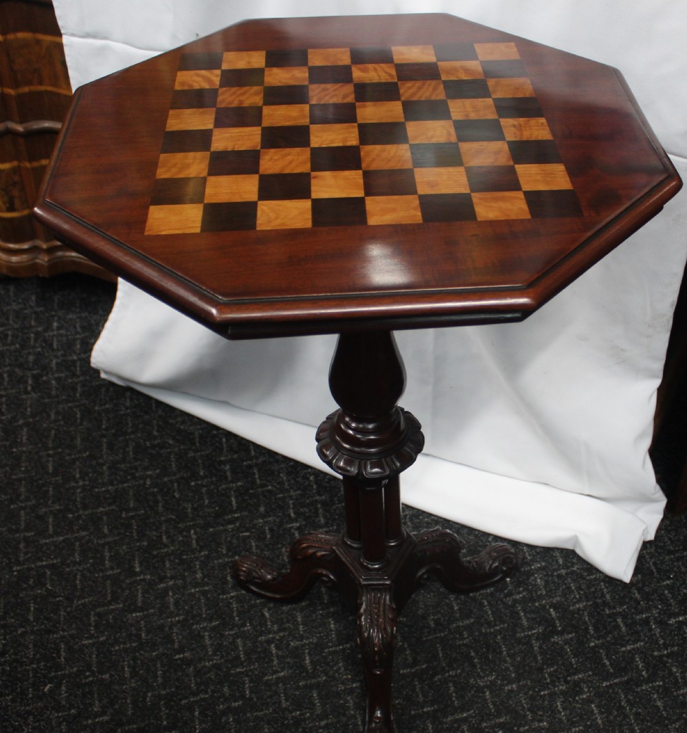 An octagonal mahogany games table featuring an inlaid chessboard top on a central turned pedestal with carved tripod legs.