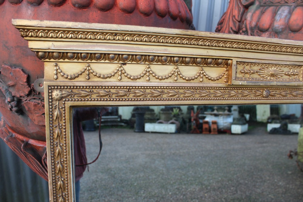 A large rectangular antique giltwood mirror decorated with classical egg-and-dart moulding, draped swag motifs, and fluted pilaster columns. View II