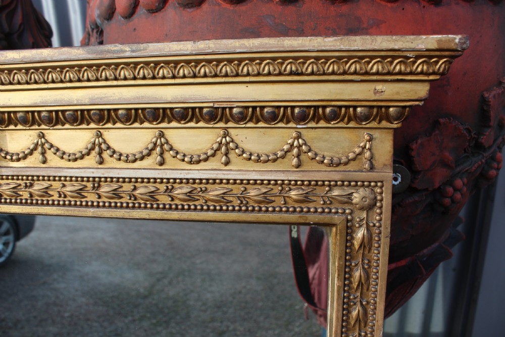 A large rectangular antique giltwood mirror decorated with classical egg-and-dart moulding, draped swag motifs, and fluted pilaster columns. View III