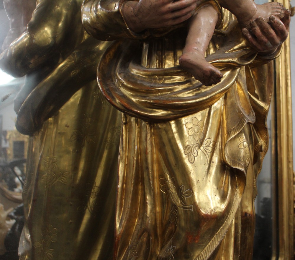 A carved wooden statue depicting Saint Joseph holding the infant Jesus, finished with gold leaf gilding and painted features atop a cherub base. View III