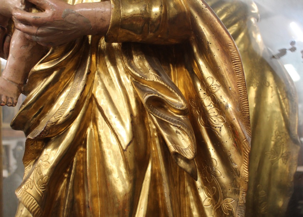 A carved wooden statue depicting Saint Joseph holding the infant Jesus, finished with gold leaf gilding and painted features atop a cherub base. View V