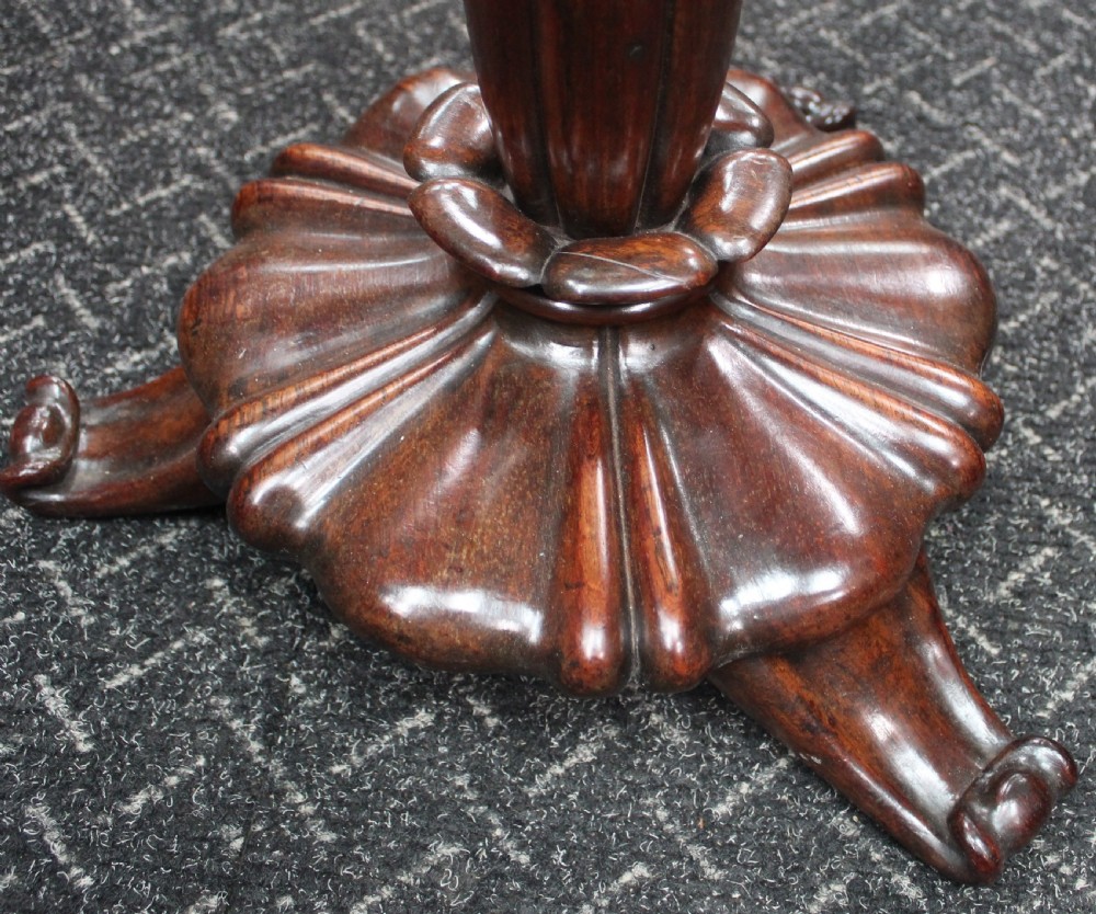 A dark rosewood circular wine table featuring a spindled gallery rim, a turned column stem, and a carved lobed base. View V