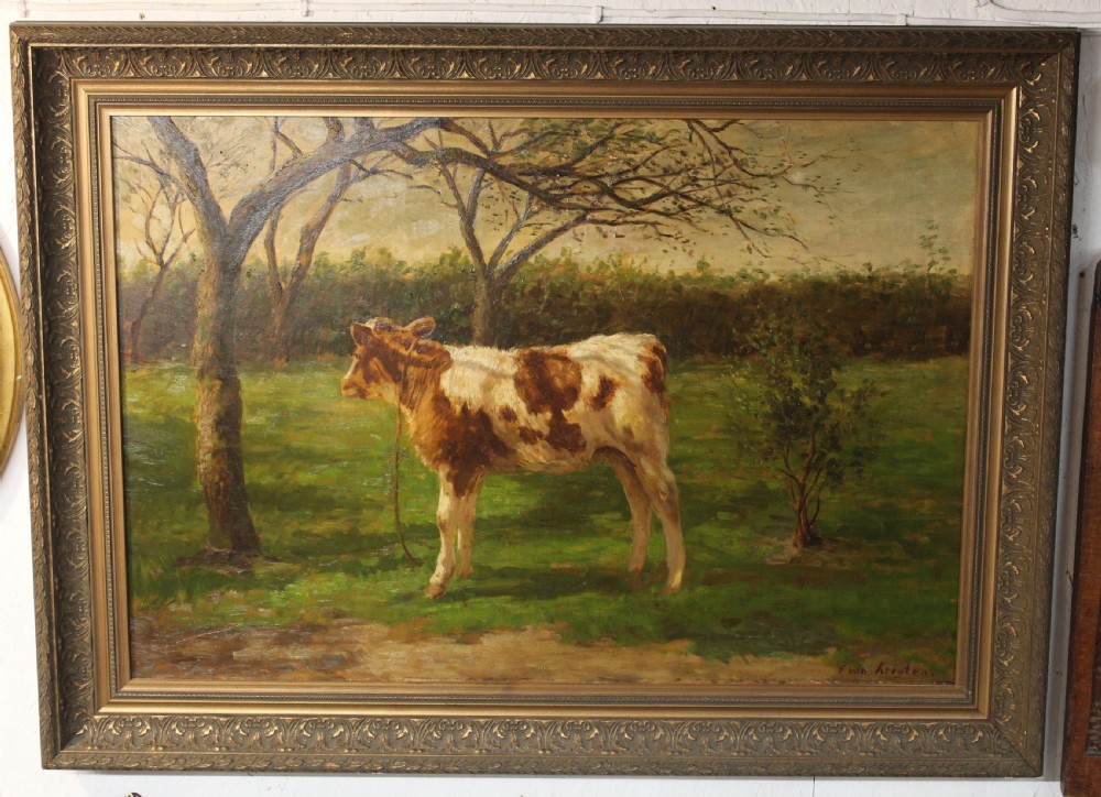 An oil painting on canvas depicting a brown and white calf standing in a green field surrounded by trees, housed within an ornate gilded frame.