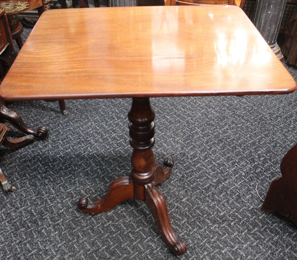 An antique mahogany tilt-top wine table shown with its top tilted upright on a turned pedestal stem and tripod scrolled legs. View II