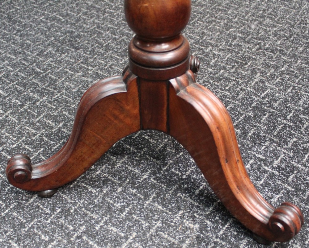 An antique mahogany tilt-top wine table shown with its top tilted upright on a turned pedestal stem and tripod scrolled legs. View IV