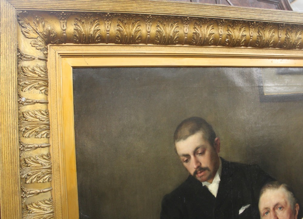 A large antique oil painting depicting two gentlemen in dark suits examining documents near a desk, set in an ornate gilded frame. View II