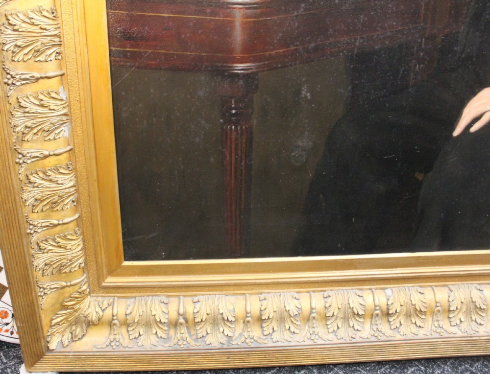 A large antique oil painting depicting two gentlemen in dark suits examining documents near a desk, set in an ornate gilded frame. View III