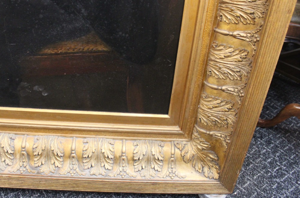 A large antique oil painting depicting two gentlemen in dark suits examining documents near a desk, set in an ornate gilded frame. View IV