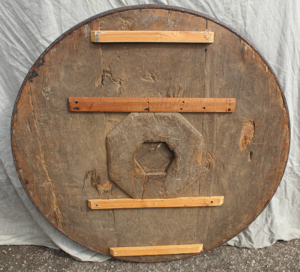 A circular hand-carved wooden relief plaque depicting the Madonna and Child surrounded by a carved floral border. View V