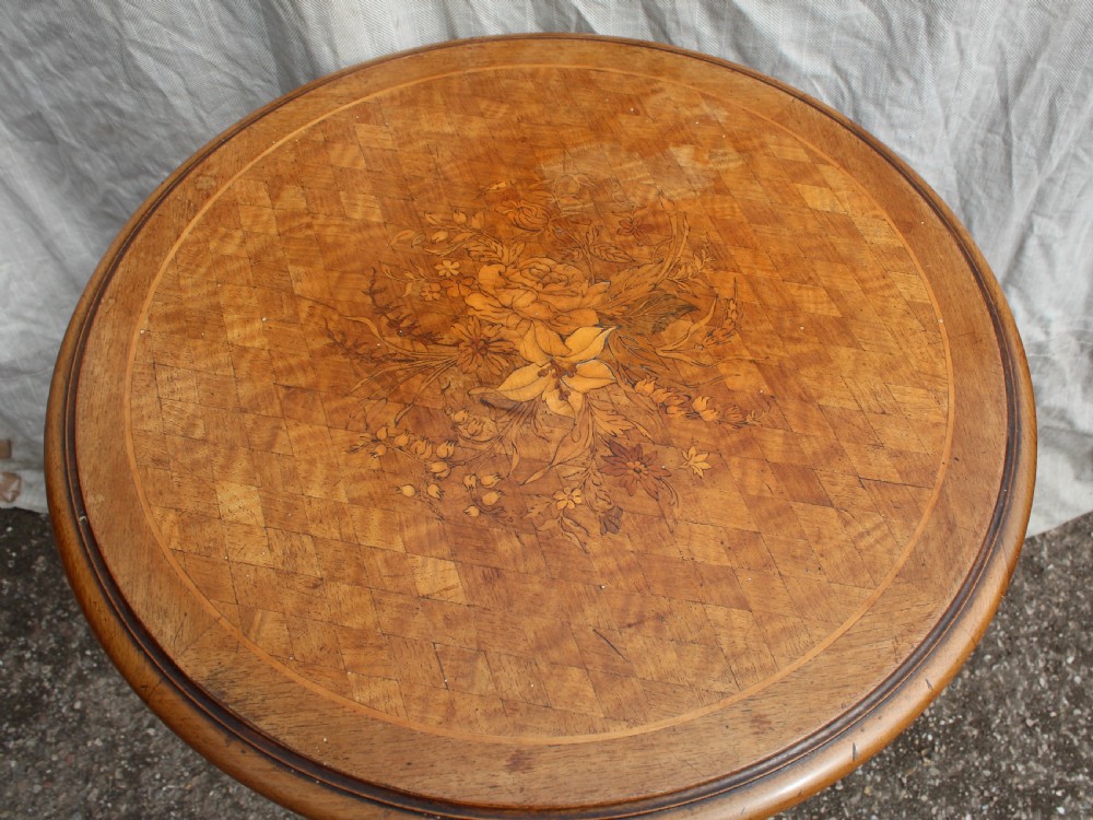 A circular antique wine table with a light parquetry inlaid top featuring a floral central motif on a carved dark mahogany tripod pedestal. View II