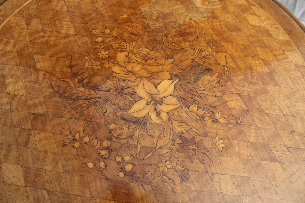 A circular antique wine table with a light parquetry inlaid top featuring a floral central motif on a carved dark mahogany tripod pedestal. View III