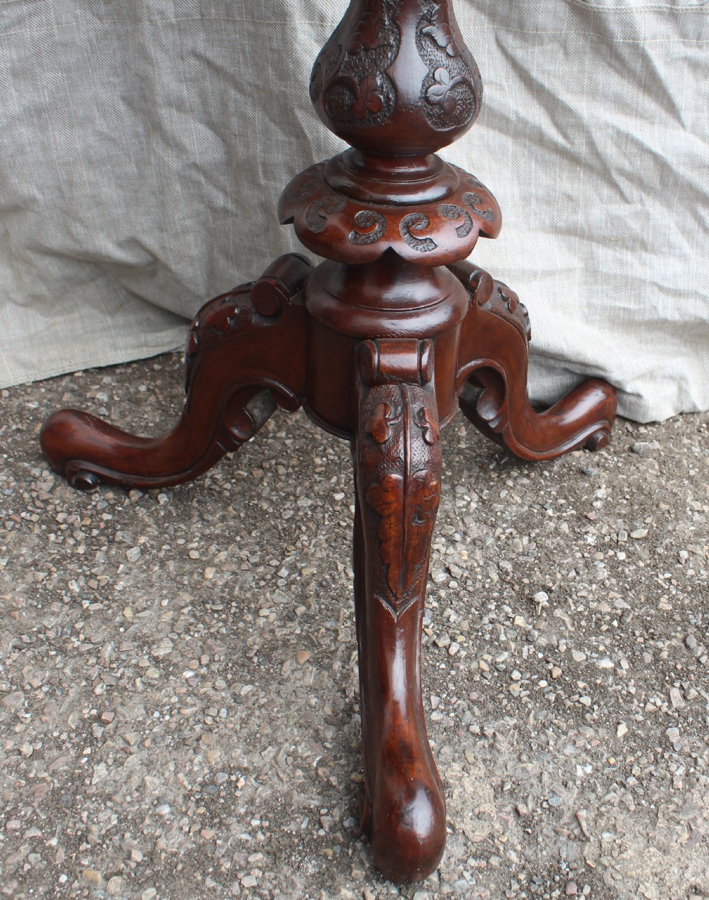 A circular antique wine table with a light parquetry inlaid top featuring a floral central motif on a carved dark mahogany tripod pedestal. View V