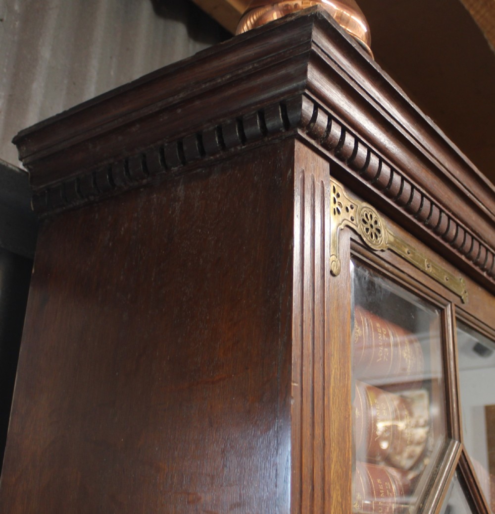 A large English oak glazed bookcase featuring three upper glass doors with geometric mullions above three drawers and three geometric panelled cupboard doors with brass mounts. View IV