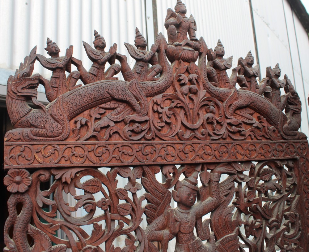 A three-panel dark wood folding screen featuring intricate hand-carved openwork lattice, floral scrolls, mythological figures, and a decorative crest. View II