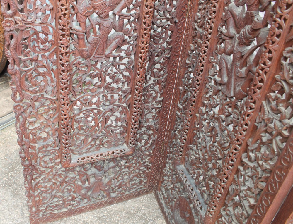 A three-panel dark wood folding screen featuring intricate hand-carved openwork lattice, floral scrolls, mythological figures, and a decorative crest. View IV