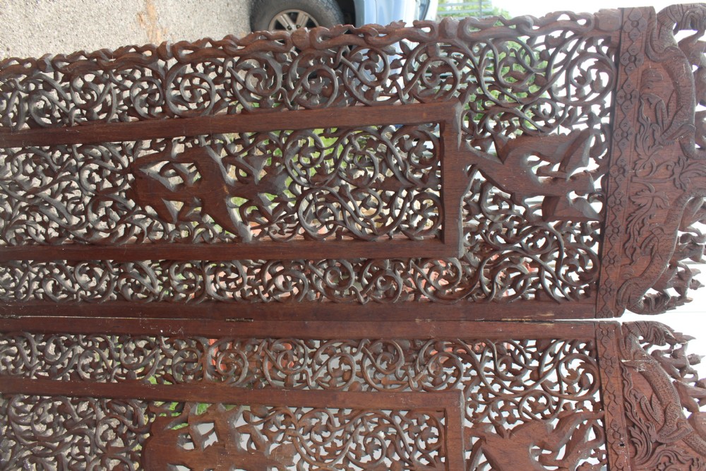 A three-panel dark wood folding screen featuring intricate hand-carved openwork lattice, floral scrolls, mythological figures, and a decorative crest. View VIII