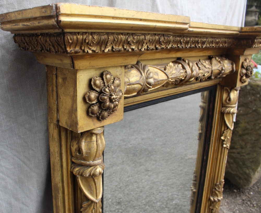 A rectangular antique giltwood pier mirror with fluted side columns, rosette medallions, and a stepped breakfront cornice. View IV