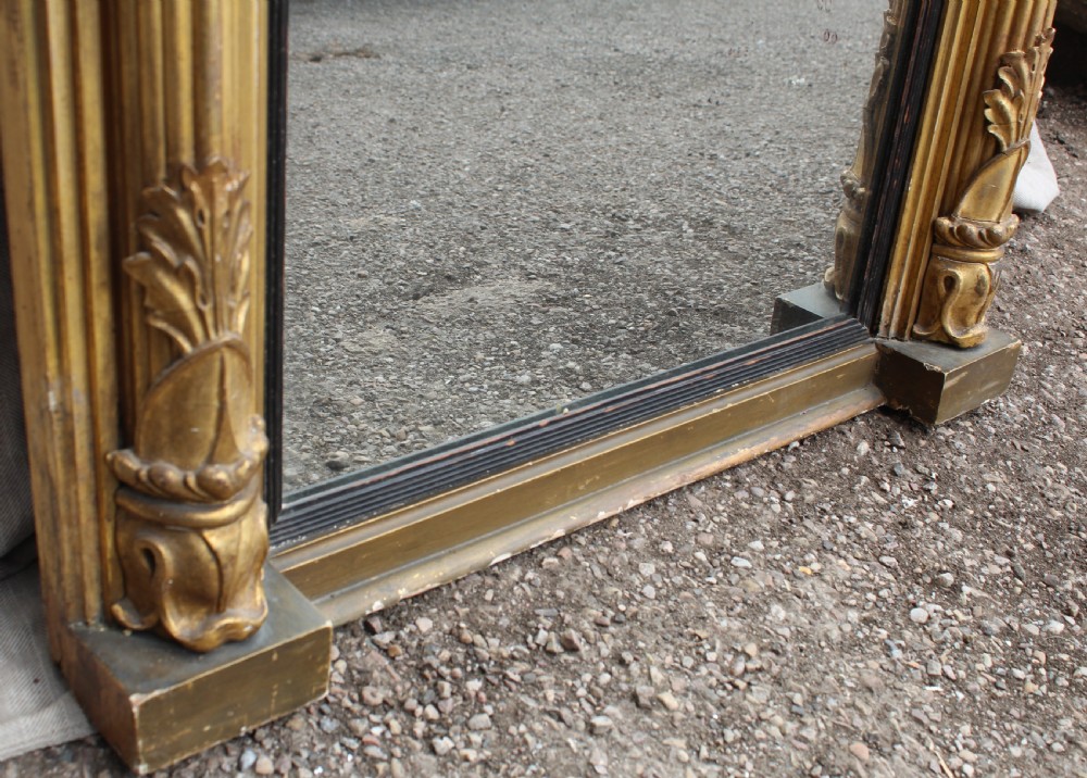 A rectangular antique giltwood pier mirror with fluted side columns, rosette medallions, and a stepped breakfront cornice. View V