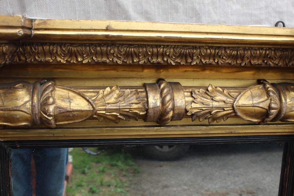 A rectangular antique giltwood pier mirror with fluted side columns, rosette medallions, and a stepped breakfront cornice. View VII