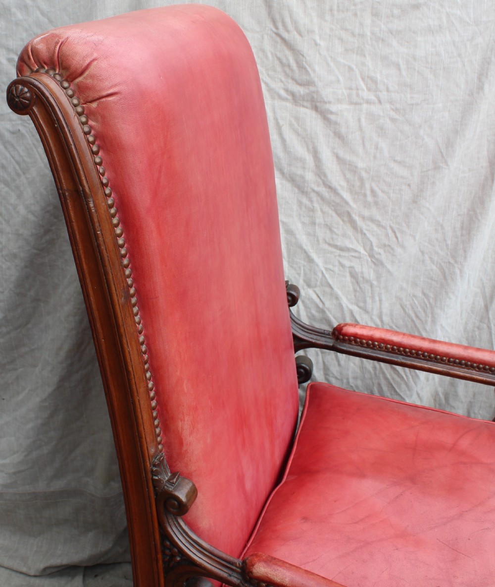 A pair of French armchairs upholstered in red leather with dark carved wood frames featuring cherub figures on the arm supports. View III