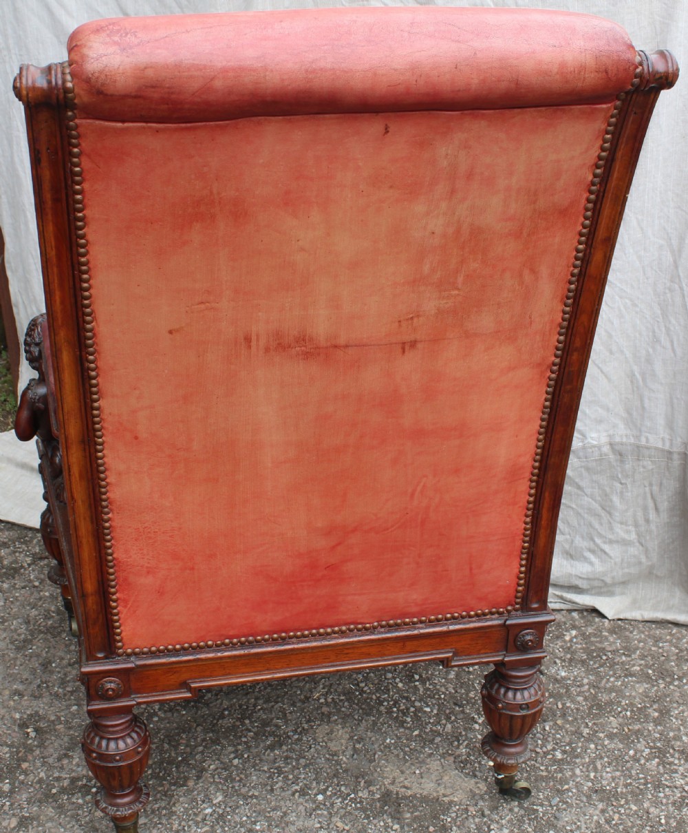 A pair of French armchairs upholstered in red leather with dark carved wood frames featuring cherub figures on the arm supports. View IX