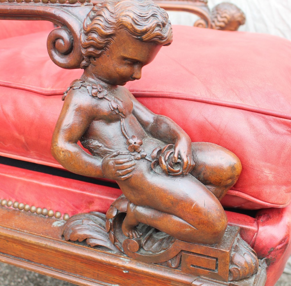 A pair of French armchairs upholstered in red leather with dark carved wood frames featuring cherub figures on the arm supports. View XI