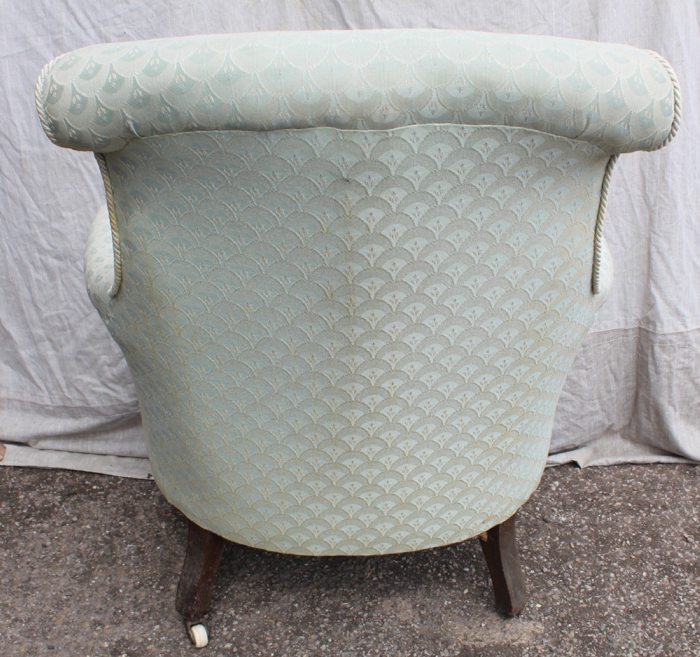 Victorian low upholstered armchair featuring pale duck egg blue patterned fabric with light rope piping and turned dark mahogany legs on ceramic castors. View IV