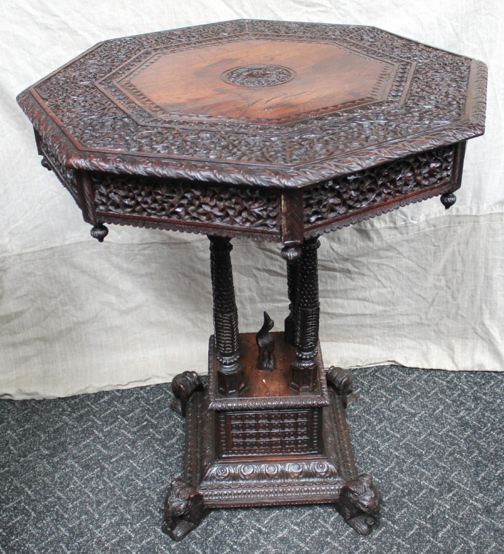 A dark brown hand-carved octagonal wooden occasional table featuring turned pillars and carved elephant head feet. View II