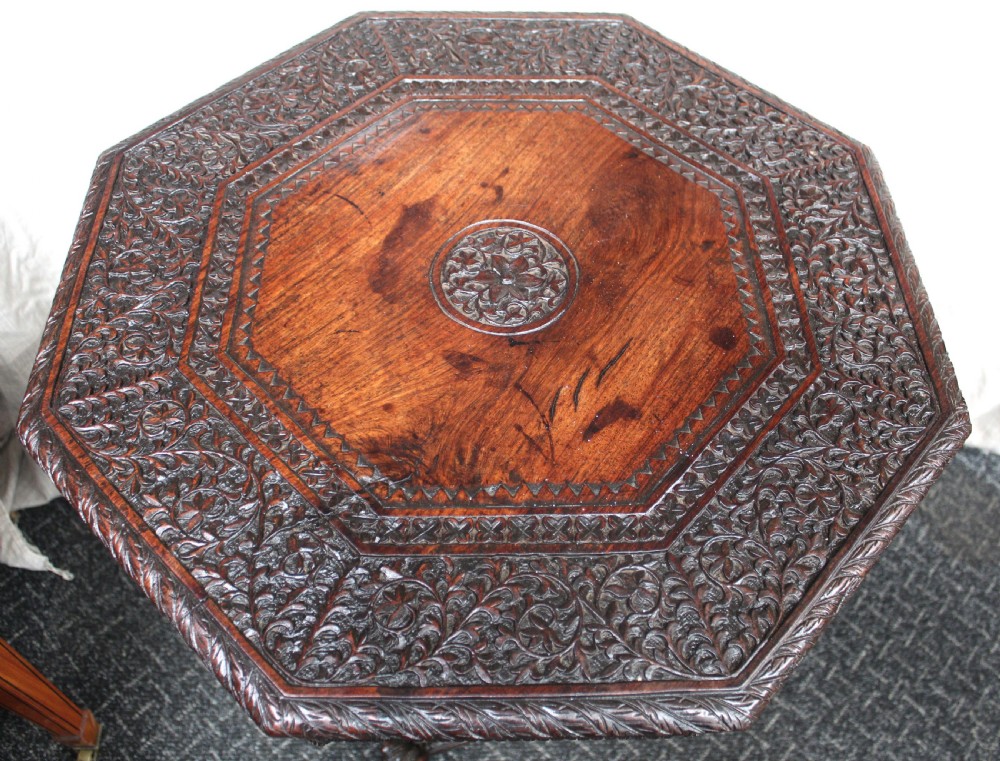 A dark brown hand-carved octagonal wooden occasional table featuring turned pillars and carved elephant head feet. View III