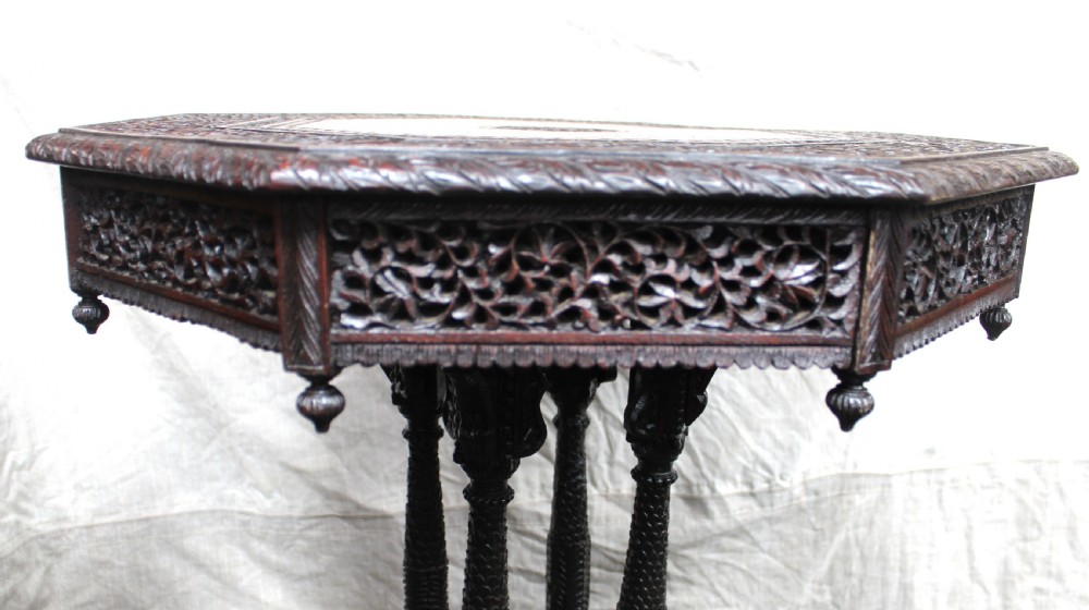 A dark brown hand-carved octagonal wooden occasional table featuring turned pillars and carved elephant head feet. View IV