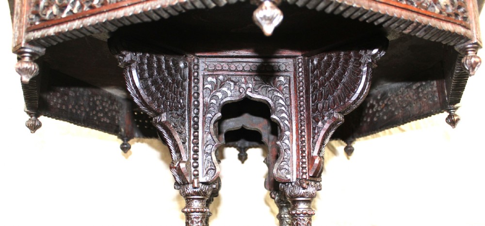 A dark brown hand-carved octagonal wooden occasional table featuring turned pillars and carved elephant head feet. View V