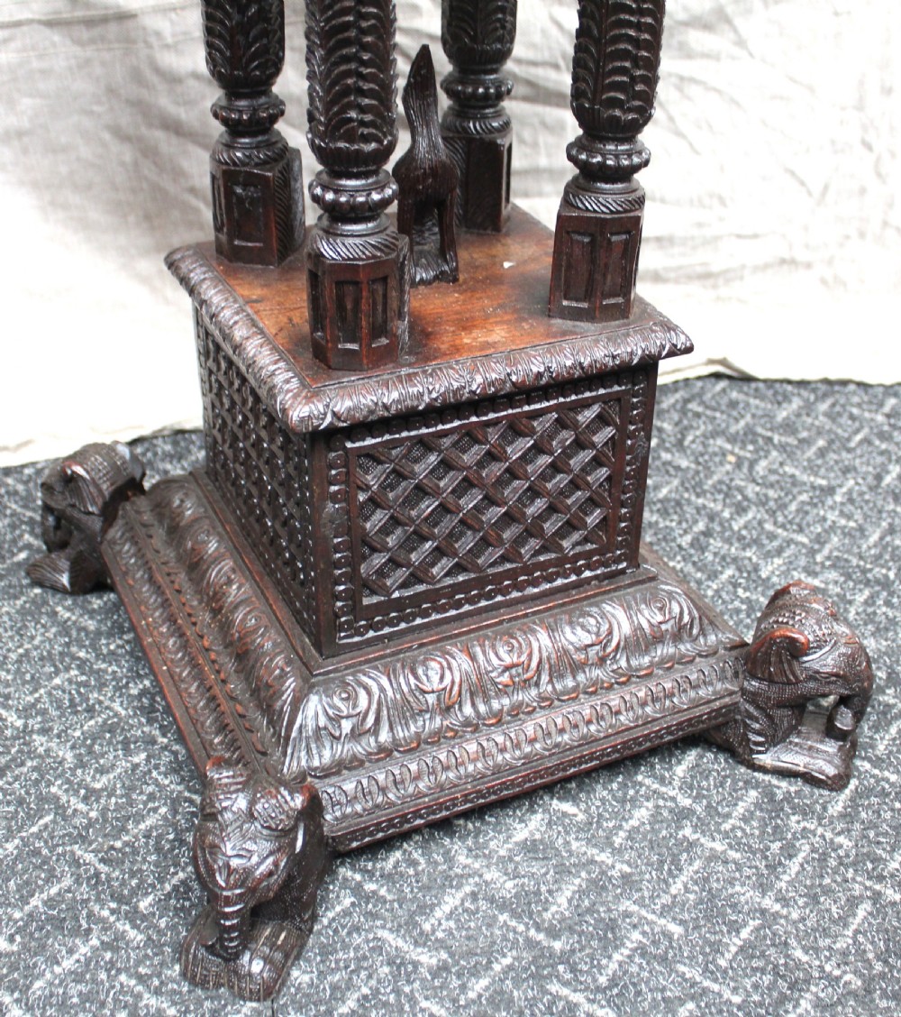 A dark brown hand-carved octagonal wooden occasional table featuring turned pillars and carved elephant head feet. View VII