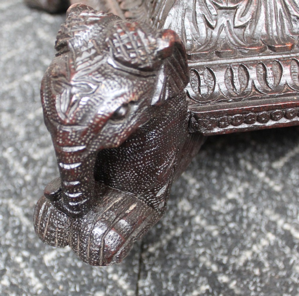 A dark brown hand-carved octagonal wooden occasional table featuring turned pillars and carved elephant head feet. View VIII