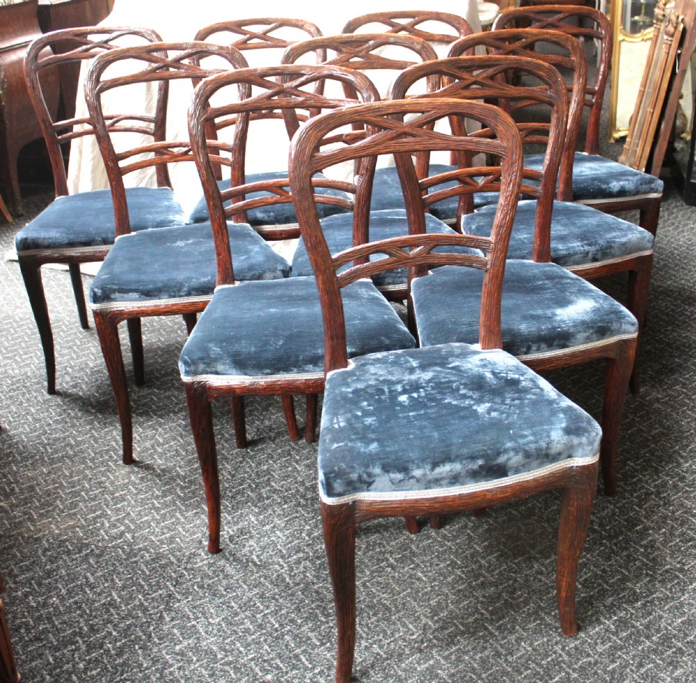 Set of ten dark brown faux bois dining chairs with rustic branch-like carved frame backrests and blue velvet upholstered seats.