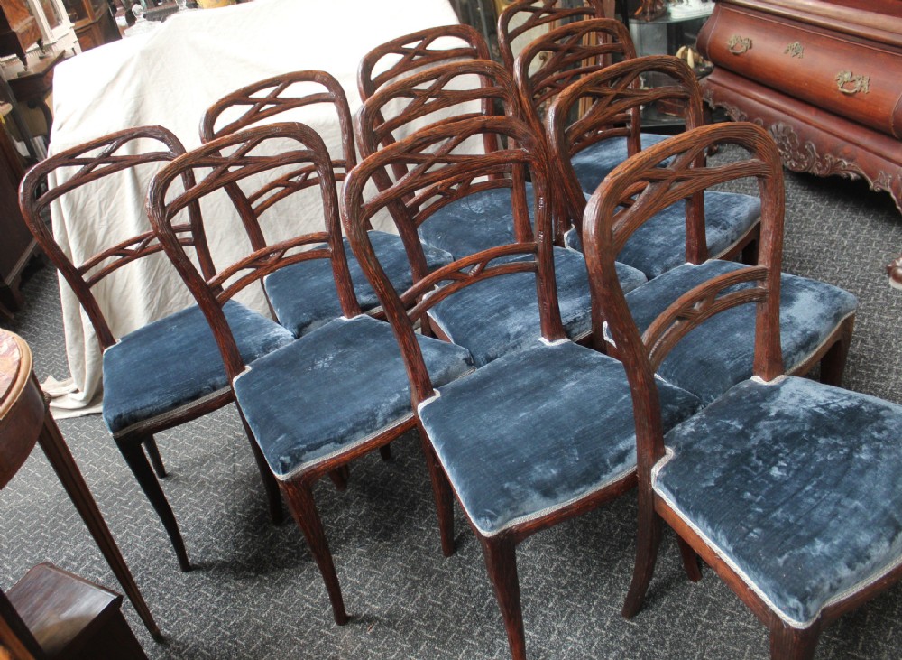 Set of ten dark brown faux bois dining chairs with rustic branch-like carved frame backrests and blue velvet upholstered seats. View II
