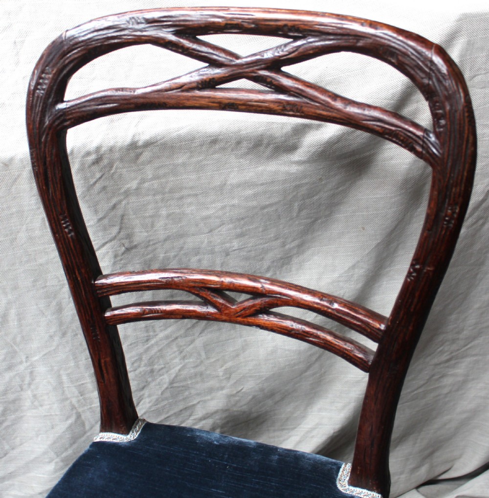 Set of ten dark brown faux bois dining chairs with rustic branch-like carved frame backrests and blue velvet upholstered seats. View V