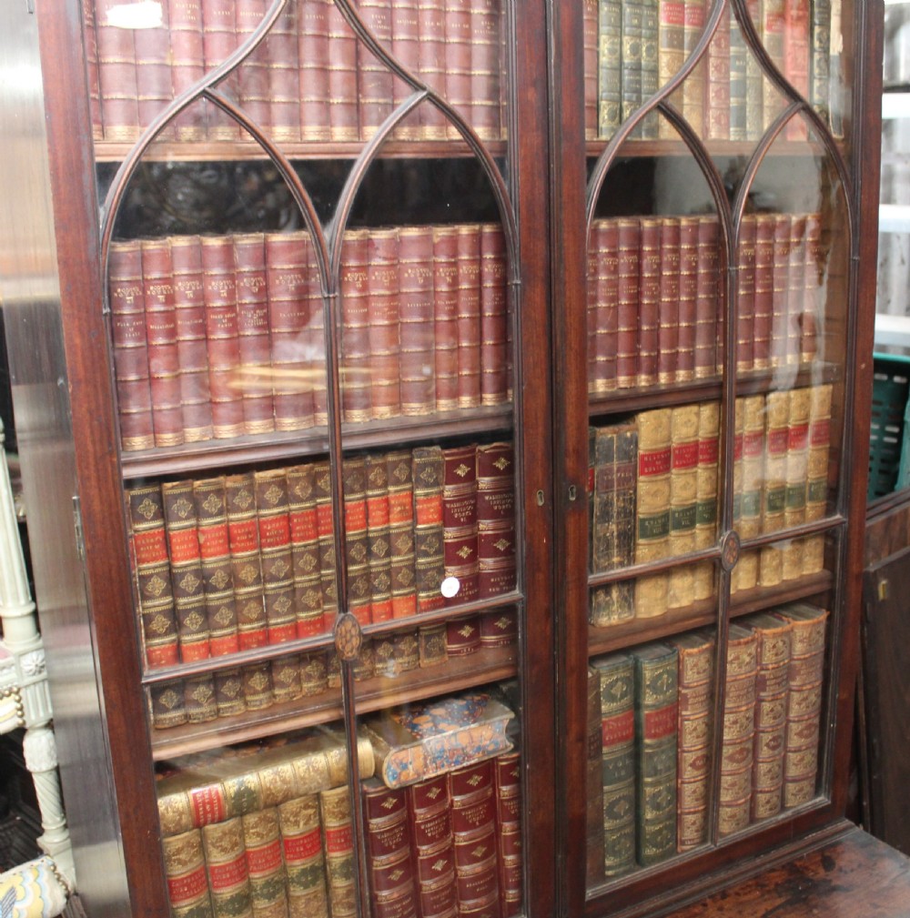 A dark mahogany Georgian secretaire bookcase featuring glazed upper doors with astragal tracery above a chest of four drawers with brass oval handles. View IV