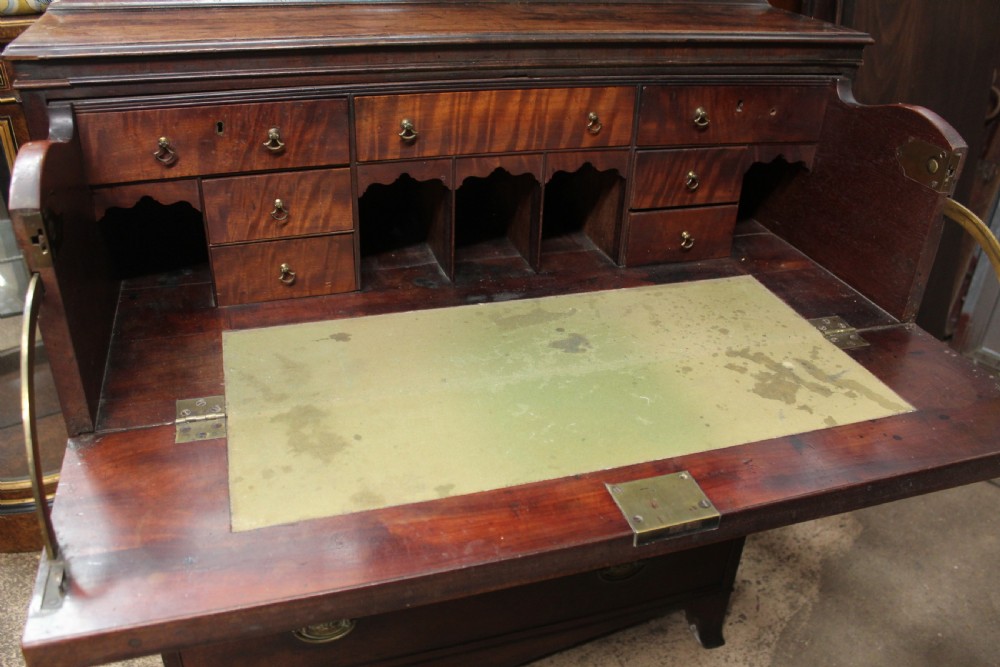 A dark mahogany Georgian secretaire bookcase featuring glazed upper doors with astragal tracery above a chest of four drawers with brass oval handles. View VI