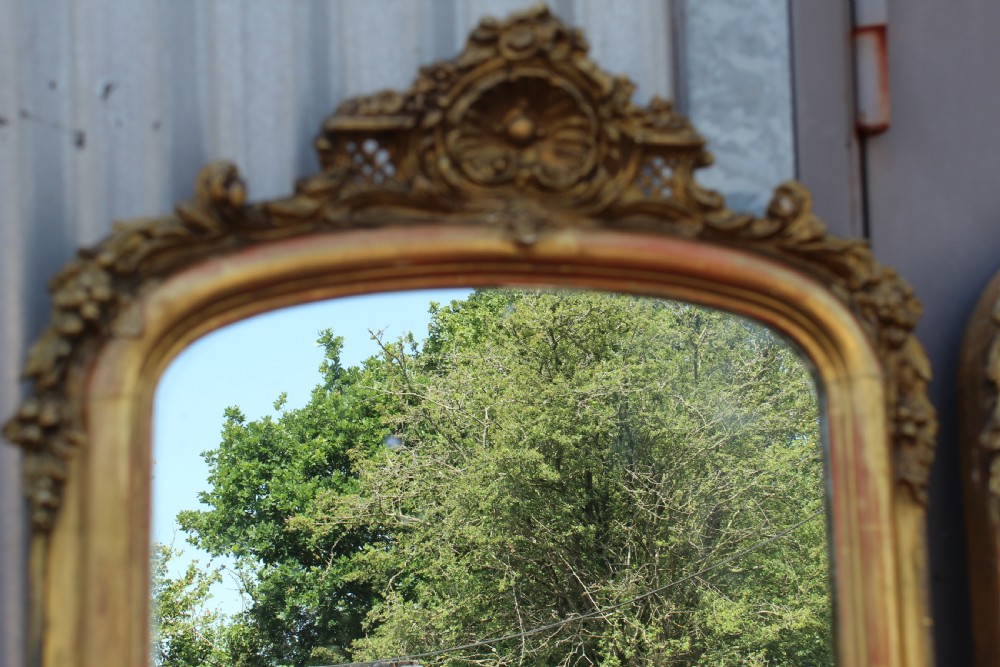 A pair of tall French giltwood pier mirrors featuring rounded arched tops with carved decorative crests and moulded frames. View II